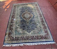 Photo of the full rug laid flat showing pattern and condition with sunlight.