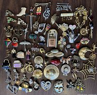 Full lot overview showing 40+ vintage novelty brooches arranged on a dark wood surface, displaying various whimsical and playful designs.