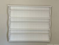Front view of the white Pottery Barn Kids wall shelf showing four shelves with beadboard back and curved sides.