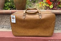 Front side of the brown leather suitcase showing handles and overall shape