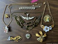 Overview of 10 jewelry pieces including necklaces, brooches, and pendants showcasing various animal and floral designs.