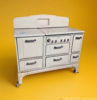 Front view of vintage cream Wedgewood stove showing multiple compartments, oven, and control knobs, cream enamel finish, metal handles, and caster wheels on legs.