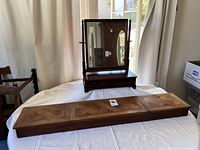 Overall view of vintage mahogany tilt mirror with drawer and oak parquet dresser topper on white surface.
