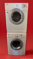 Front view of stacked Whirlpool washer and dryer against red background