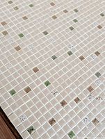 Close-up image of the mosaic tile top showing cream, green, brown and speckled square tiles arranged in a grid pattern with light grout lines.