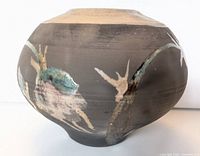 Front angle showing vase body, Raku glaze decoration with earthy black and beige tones and green glaze accents.