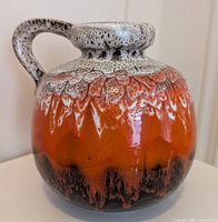 Front view of Blue Mountain Pottery jug showing orange and black glaze with white speckled top and handle