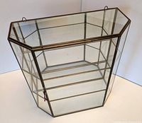 View of the brass frame and glass panels showing the geometric shape of the cabinet.