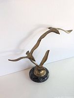 View of the brass seagull sculpture from the front showing two birds and the polished stone base.