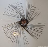 Top view of the full metal starburst wall sculpture showing thin radial spokes and hammered metal centerpiece.