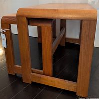 Side view of three nesting tables stacked, showing leg construction and joinery