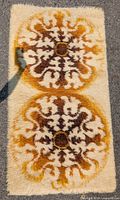 Full view of vintage rya rug laid flat to show entire design with two large circular patterns in mustard yellow, brown and cream tones.