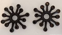 Top view showing two starburst designed cast iron candle holders, each with round arms radiating outward.