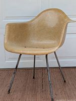 Front view of tan fiberglass arm shell chair on steel rod legs