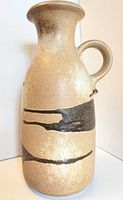 Front side view of large beige and brown West German pottery vase with black drip glaze detail and single handle.