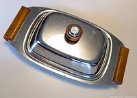 Oblique top view showing chrome finish, wood handles, and clear knob on lid