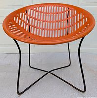 Front view of the orange plastic bowl seat on black metal wire base