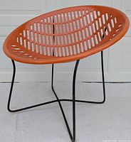 Side view of orange circular slatted seat on black metal base