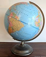 Front and side view of vintage George F. Cram Company Imperial globe showing South America and Atlantic Ocean areas with metal base and measuring ring.