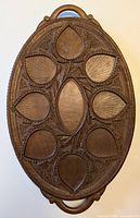 Top view of oval carved wooden serving tray with leaf motifs.