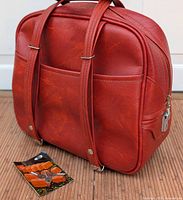 Front side view of vintage red Dionite overnight bag with two carry straps and lock key attached.