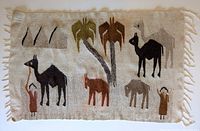 Front view of the rug showing camels, palm trees, and human figures in earthy colors on a beige background with fringed edges.