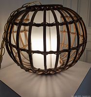 Front view of rattan swag light lit up showing woven texture and light diffusion.