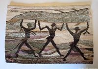 Front view of woven wool tapestry showing three dark silhouette figures carrying a large object.