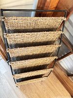 Side angled view showing the six woven rattan slots and black metal frame.