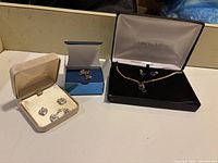 Image showing three jewelry boxes containing various pieces of costume jewelry including necklaces and earrings.