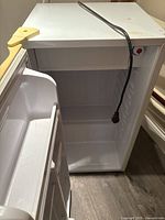 Mini bar refrigerator open showing inside compartment and door storage.