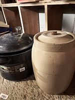 Photo of the black speckled metal canning pot next to the beige vintage ceramic pickling jar with lid, showing size and condition.