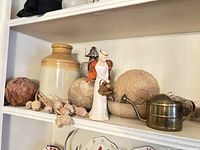 Shelf with assorted decorative items including ceramic jug, dried botanicals, figurine, natural fiber balls, and vintage oil lamp.