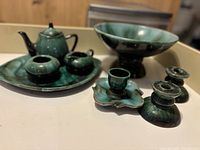 Wide shot showing full assortment of Blue Mountain Pottery items including teapot, sugar bowl, creamer, bowl, candle holders, tray, and unique shaped plate