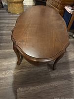 Top view of the wooden oval coffee table showing smooth surface with minor scratches and sculpted edges