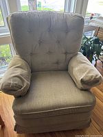 Front view of beige fabric armchair showing tufted backrest, cushioned seat and armrests