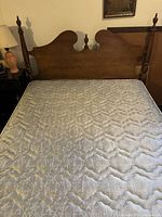 Full/double-size wooden headboard with turned finials and mattress shown in front