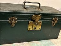 Closed vintage green metal toolbox showing front and latch with keyhole and side clasps.