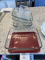 Top view of stacked glass and ceramic baking dishes showing different sizes and the red ceramic base dish with Anchor Hocking logo.