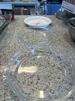 Overview of the three dishes showing two clear glass round dishes and one white ceramic dish on countertop.