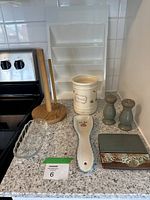 Countertop with paper towel holder, ceramic crock, salt and pepper shakers, glass dish, bread board, spoon rest, and two rectangular dish pieces.