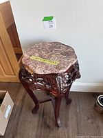 Pedestal stand with marble top and carved wooden legs shown from stand perspective.