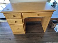 Full view of natural finish wooden desk showing four drawers and open leg space.