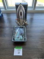 Philips Mistral iron standing in front of its original box, long beige power cord coiled at the base, placed on a wooden surface near windows.