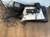 Sony Blu-ray player with remote, power adapter, cables, and user manual on a wooden floor.