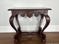 Front view of antique style Asian painted mahogany table on hardwood floor against white wall.