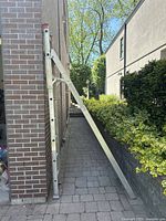 Side view of the extended aluminum folding and extension ladder propped against a brick wall.