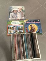 Top view of vinyl records including Simon and Garfunkel, Disney Lady and the Tramp, Disney Peter Pan, and others stacked upright