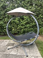 Front view of circular metal frame with black fabric seat and beige canopy