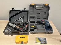 Top view photo showing Ryobi 12V cordless drill in grey carry case, vintage Craftsman Dremel tool with grinding shelves inside black case, Dewalt yellow drill bit case, and small clear plastic pack with fine point screwdrivers.